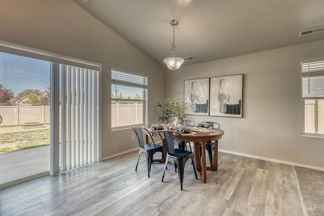dining room with visible vents, baseboards, light wood finished floors, and vaulted ceiling