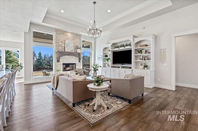 living area featuring dark wood-style floors, a fireplace, baseboards, and a raised ceiling