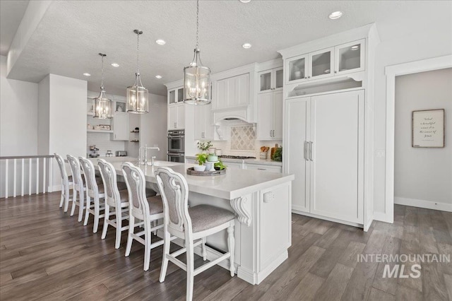 kitchen with white cabinets, backsplash, a kitchen breakfast bar, and light countertops