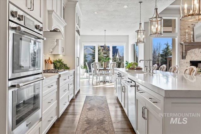 kitchen with dark wood-style floors, a textured ceiling, a sink, and white cabinets