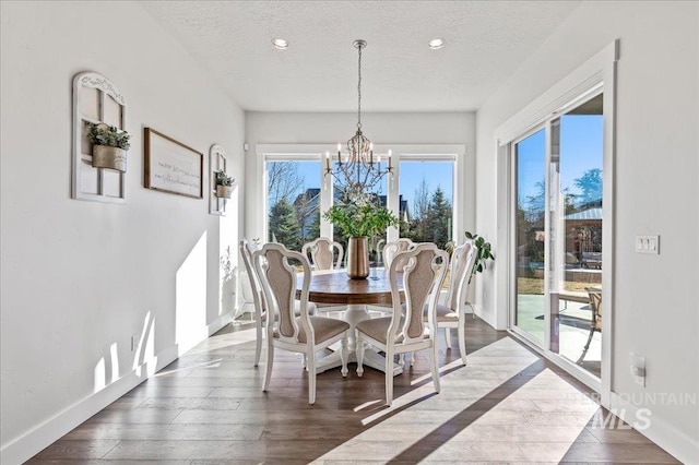 dining space with dark wood-style floors, a notable chandelier, a textured ceiling, and baseboards