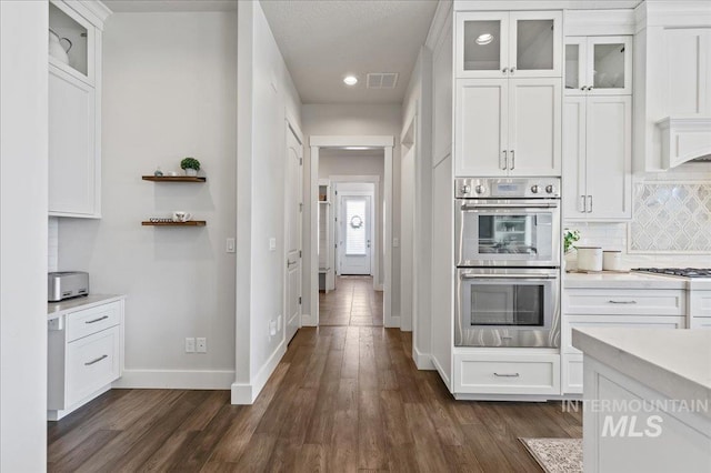 kitchen with double oven, light countertops, visible vents, and white cabinetry