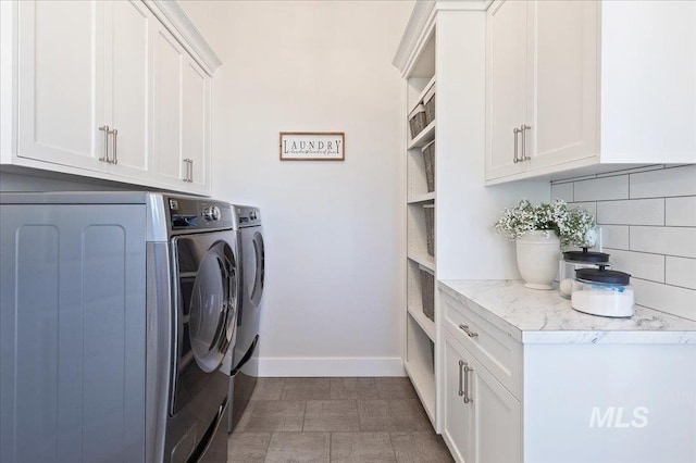 laundry room featuring washer and clothes dryer, cabinet space, and baseboards