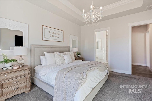 bedroom featuring carpet floors, baseboards, a raised ceiling, and ensuite bathroom