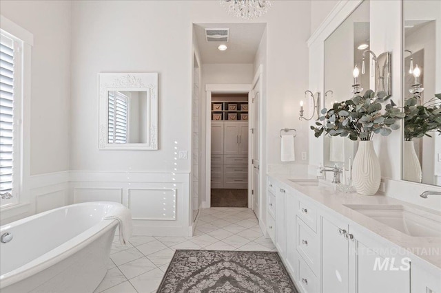 full bathroom featuring a wainscoted wall, a freestanding bath, visible vents, and a sink