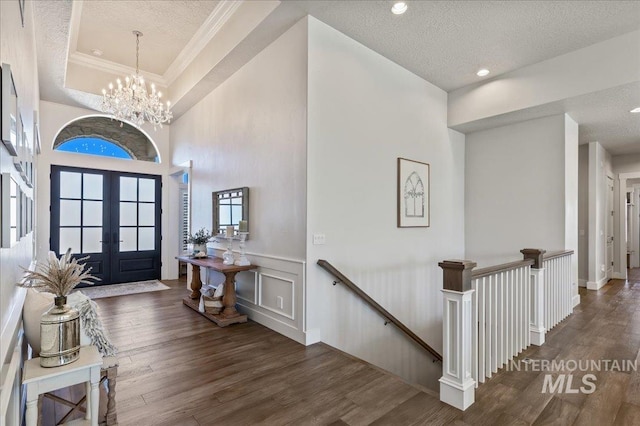 foyer with a textured ceiling, french doors, wood finished floors, and crown molding