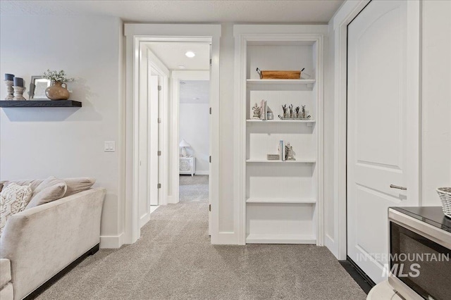 hallway featuring carpet floors, baseboards, and built in features