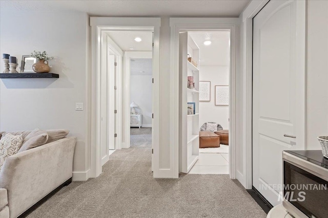 hallway featuring carpet and baseboards