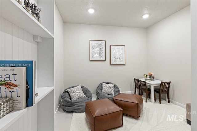 living area featuring carpet floors, baseboards, a textured ceiling, and recessed lighting