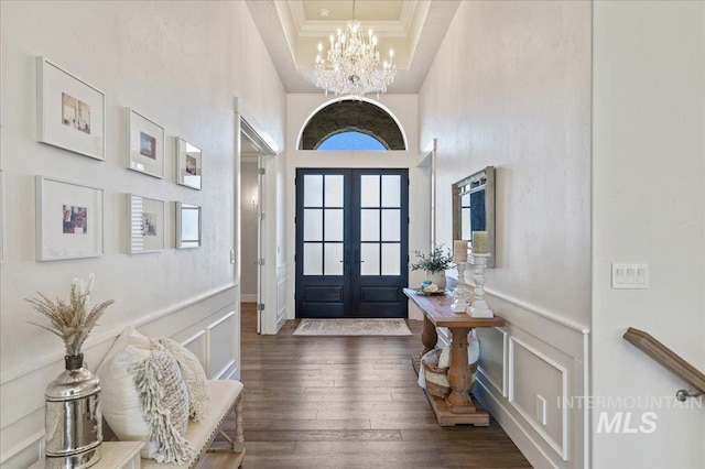 entrance foyer with a tray ceiling, crown molding, wainscoting, a chandelier, and hardwood / wood-style flooring