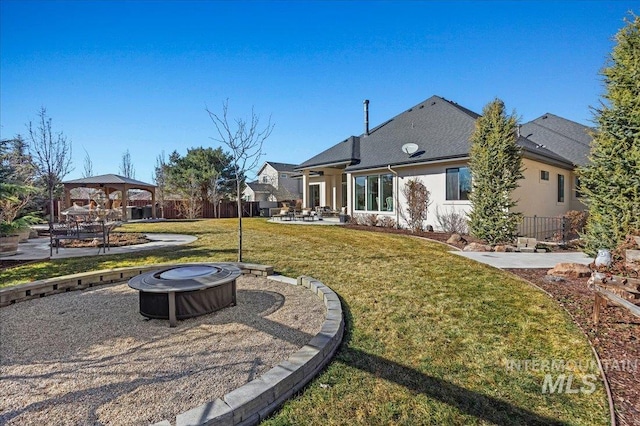 rear view of property featuring an outdoor fire pit, a patio, a yard, fence, and a gazebo