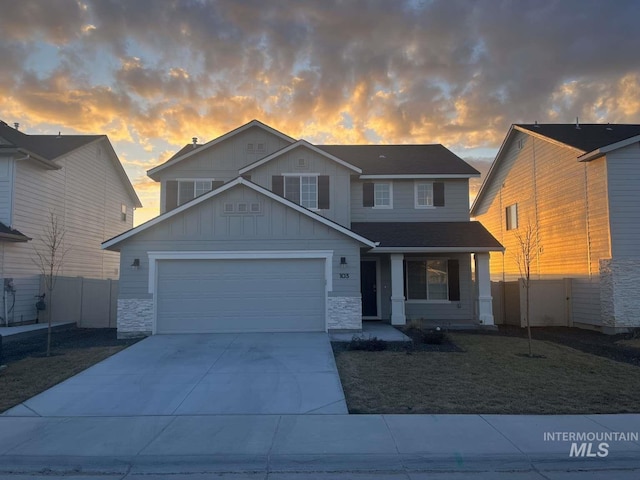 view of front of home with board and batten siding, fence, concrete driveway, a garage, and stone siding