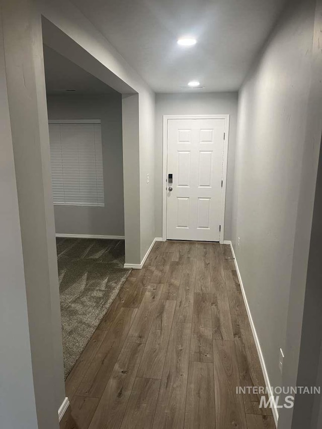 corridor featuring baseboards and wood finished floors