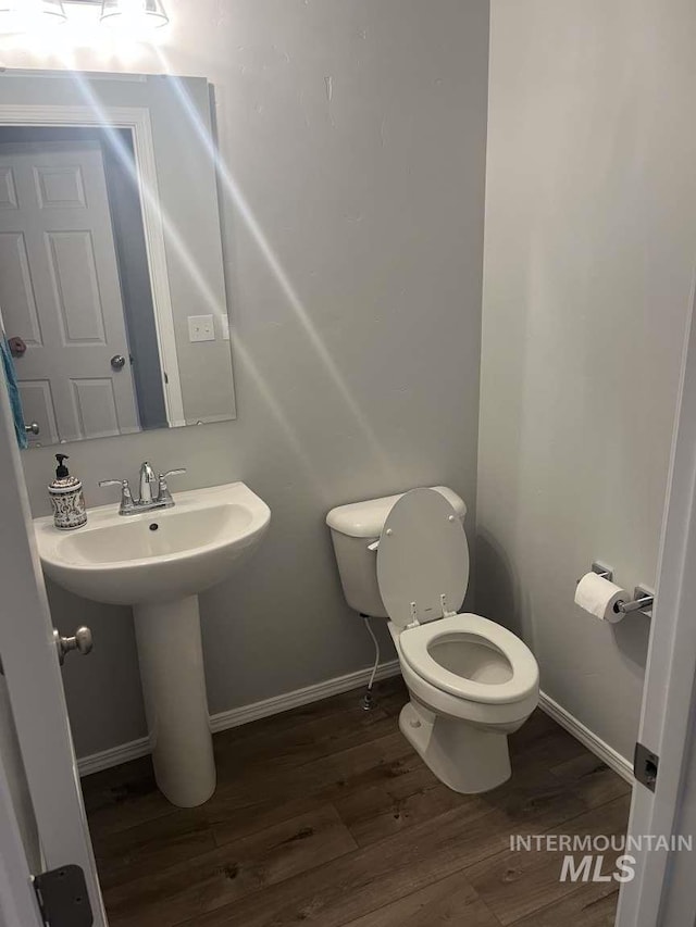 bathroom with baseboards, a sink, toilet, and wood finished floors