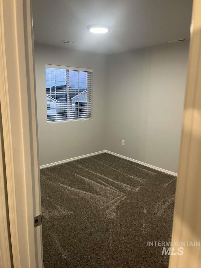 spare room featuring carpet and baseboards