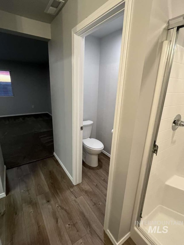 bathroom featuring toilet, a shower stall, visible vents, and wood finished floors