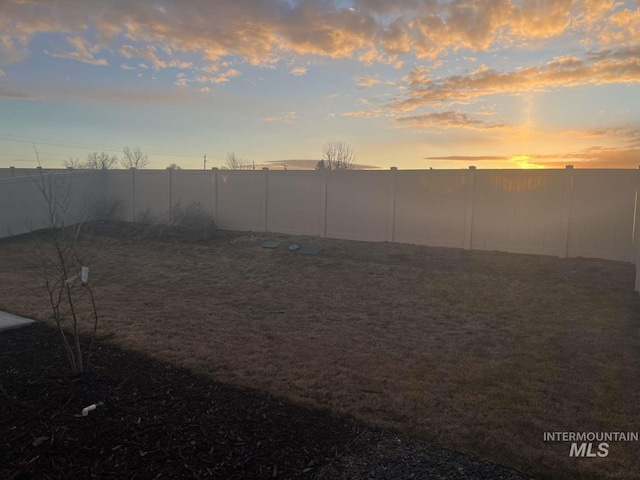 yard at dusk with a fenced backyard