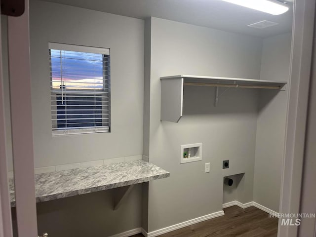 washroom with electric dryer hookup, washer hookup, dark wood finished floors, baseboards, and laundry area