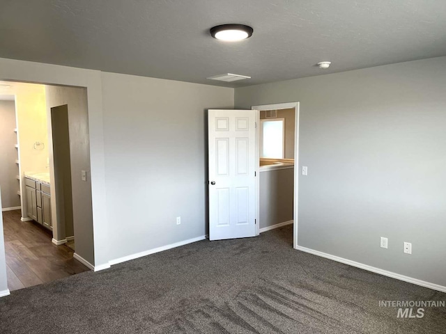 empty room with dark carpet and baseboards
