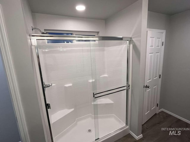 full bathroom featuring baseboards, wood finished floors, and a stall shower