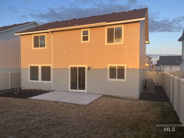 rear view of house featuring a patio area, a fenced backyard, central AC unit, and a yard