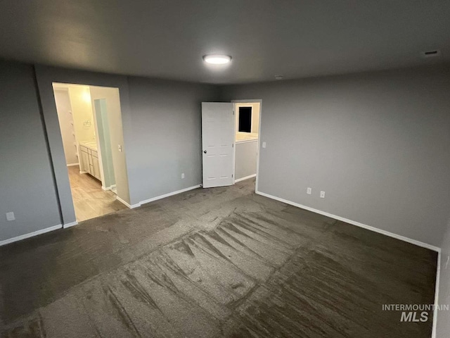 unfurnished bedroom featuring carpet flooring, baseboards, and connected bathroom