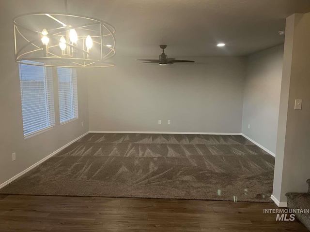 unfurnished room with carpet, recessed lighting, wood finished floors, baseboards, and ceiling fan with notable chandelier