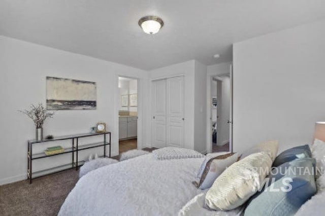 bedroom with ensuite bath, dark carpet, and a closet