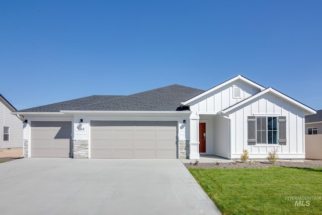 view of front facade featuring roof with shingles, an attached garage, concrete driveway, a front lawn, and board and batten siding