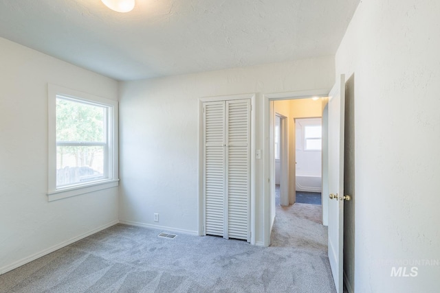 unfurnished bedroom featuring light colored carpet and a closet