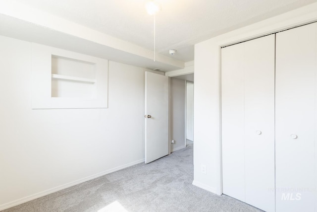 unfurnished bedroom with light carpet, a closet, and a textured ceiling