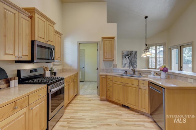9407 W Pebblestream Dr, Boise, ID 83709 - kitchen with appliances with stainless steel finishes, light brown cabinetry, high vaulted ceiling, a peninsula, and light wood finished floors