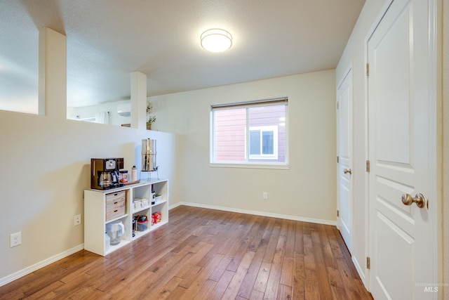 interior space with baseboards, wood finished floors, and a wall mounted air conditioner