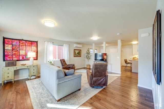 living area featuring a wall mounted AC, baseboards, and hardwood / wood-style flooring