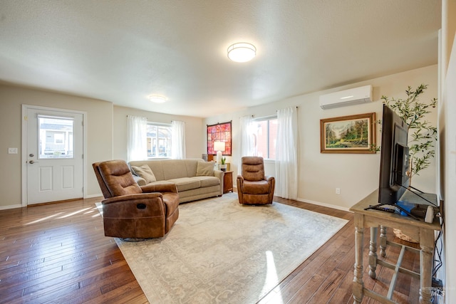 living area with dark wood-type flooring, a healthy amount of sunlight, a wall unit AC, and baseboards