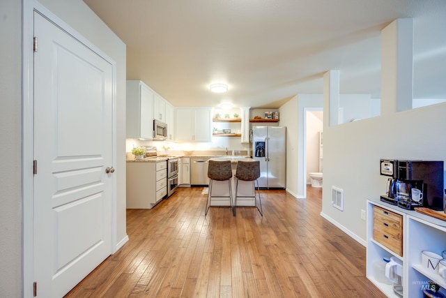 kitchen with stainless steel appliances, a kitchen island, visible vents, light wood-style floors, and open shelves