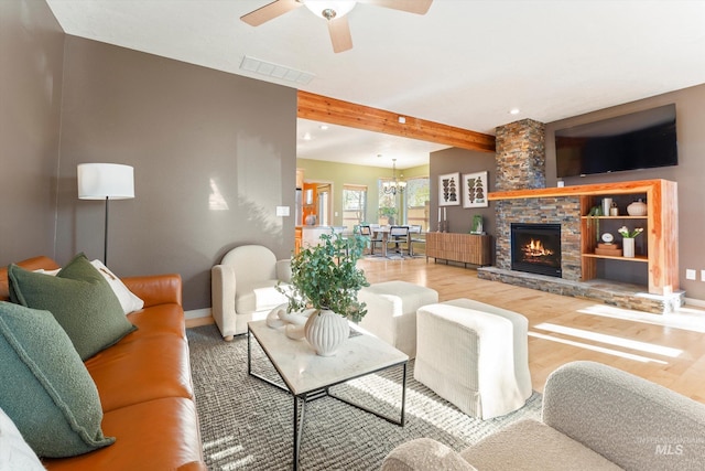 living room with a fireplace, ceiling fan with notable chandelier, wood-type flooring, and beamed ceiling