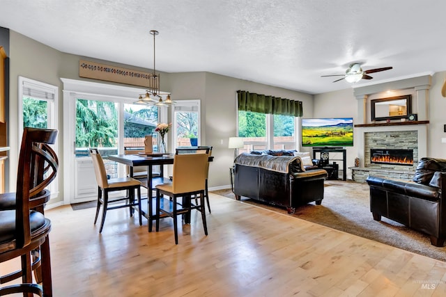 1390 E Prohaska Ct, Eagle, ID 83616 - dining room featuring ceiling fan, plenty of natural light, a stone fireplace, a textured ceiling, and light wood-style flooring