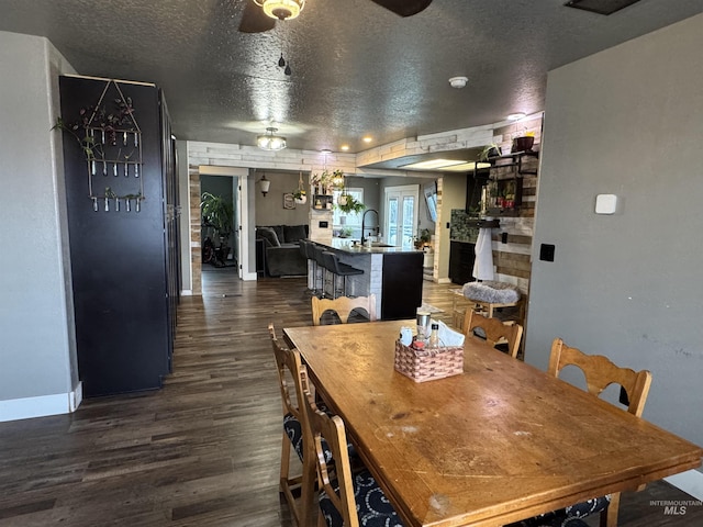 dining space with a textured ceiling, sink, and dark hardwood / wood-style floors