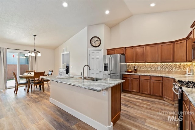 3499 S Green Basin Way, Nampa, ID 83686 - kitchen featuring appliances with stainless steel finishes, brown cabinetry, a chandelier, tasteful backsplash, and light stone counters