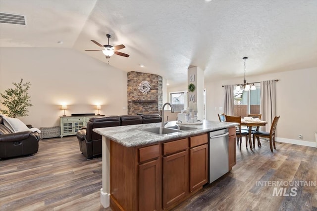 3499 S Green Basin Way, Nampa, ID 83686 - kitchen featuring open floor plan, stainless steel dishwasher, a kitchen island with sink, brown cabinetry, and lofted ceiling
