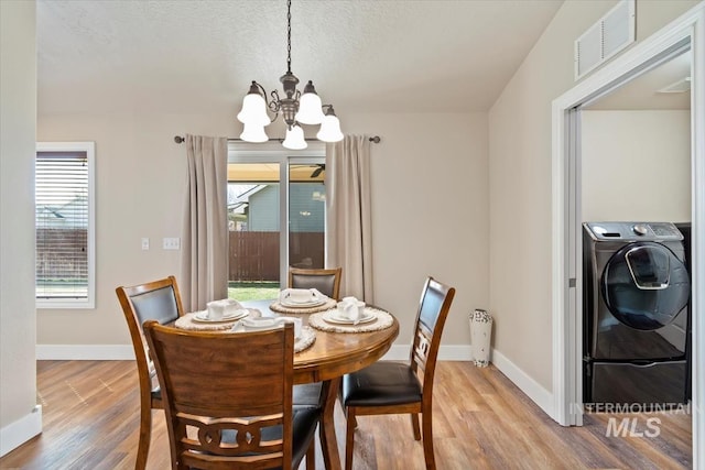 3499 S Green Basin Way, Nampa, ID 83686 - dining room featuring a chandelier, plenty of natural light, light wood-style floors, washer / dryer, and a textured ceiling