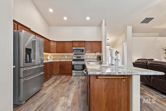 3499 S Green Basin Way, Nampa, ID 83686 - kitchen with stainless steel appliances, open floor plan, decorative backsplash, light stone counters, and wood finished floors