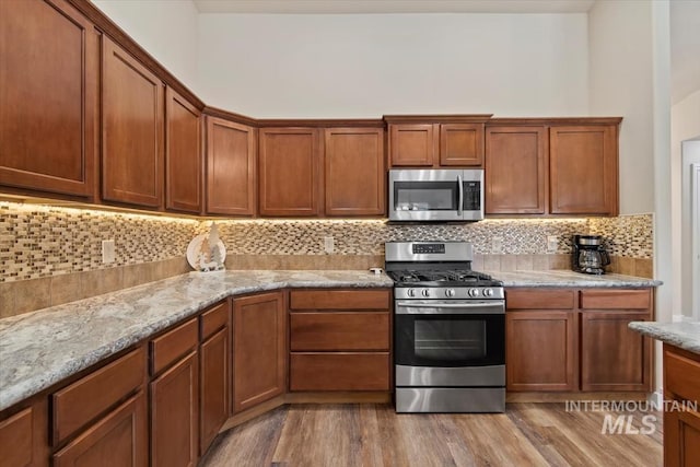 3499 S Green Basin Way, Nampa, ID 83686 - kitchen featuring appliances with stainless steel finishes, decorative backsplash, light wood-style flooring, and light stone counters