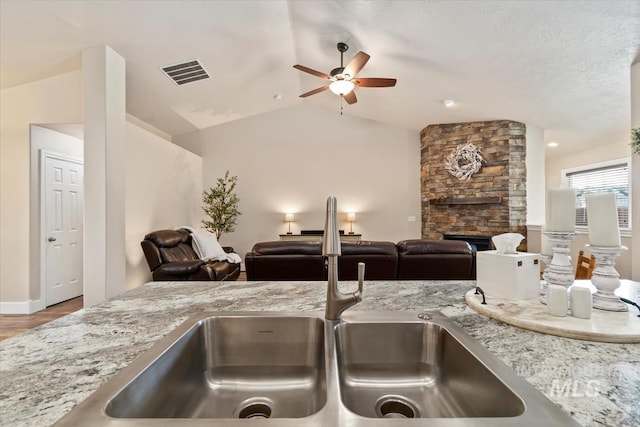 3499 S Green Basin Way, Nampa, ID 83686 - kitchen view of a ceiling fan, a stone fireplace, and light stone counters
