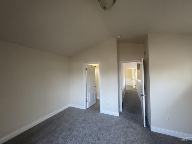 unfurnished bedroom featuring vaulted ceiling, dark colored carpet, and baseboards