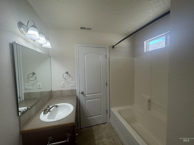 bathroom featuring vanity, a textured ceiling, visible vents, tile patterned flooring, and washtub / shower combination