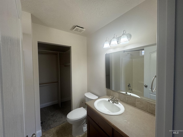 bathroom featuring toilet, vanity, visible vents, and a textured ceiling