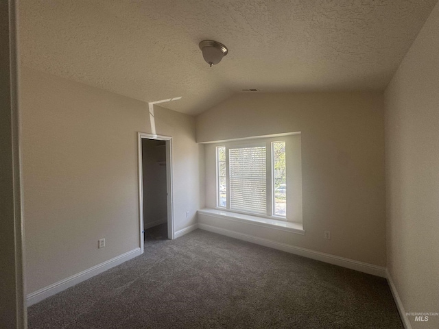 unfurnished bedroom with carpet, lofted ceiling, a textured ceiling, and baseboards