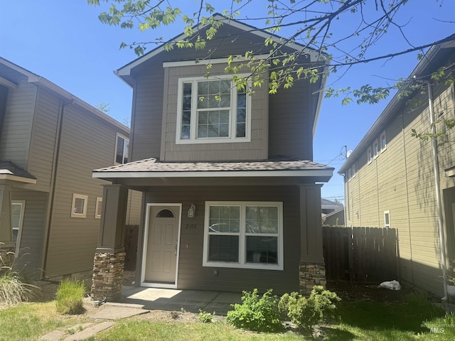 view of front of property with a porch, roof with shingles, and fence